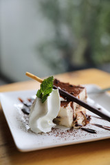 tiramisu cake dessert with cream mint and chocolate sauce on wood background