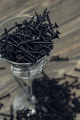 Pile of black screw nails on wooden background. Lots of screws on the table.