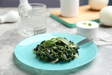 Tasty cooked spinach and fork on grey table. Healthy food