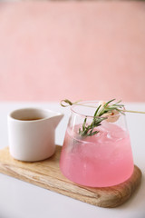 Pink cocktail with rosemary and lychee in pink background