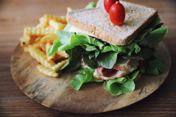 Club sandwich with ham, bacon, tomato,  cheese, eggs and fried on wood background