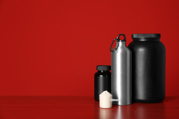 Composition with protein powder and black jars on table against red background