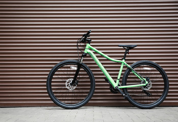 Fototapeta na wymiar New modern color bicycle near brown wall outdoors