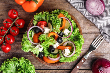 Tasty fresh Greek salad on wooden table, flat lay
