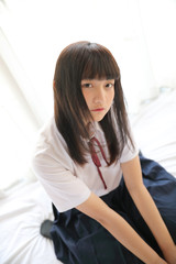 Naklejka premium Portrait japanese school girl sitting in white tone bed room