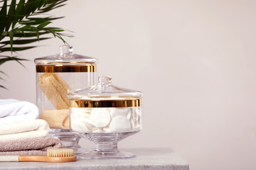 Composition of glass jar with cotton pads on table near light wall. Space for text