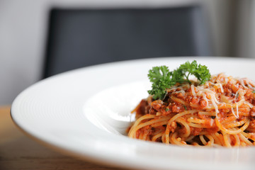 spaghetti Bolognese with minced beef and tomato sauce garnished with parmesan cheese and basil , Italian food