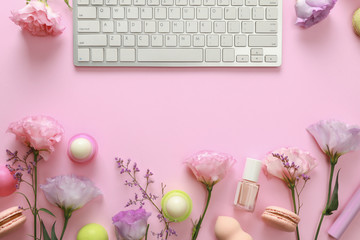 Flat lay composition with keyboard and flowers on pink background. Beauty blogger's workplace