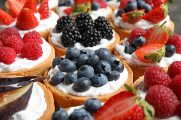 Many different berry tarts on table, closeup. Delicious pastries