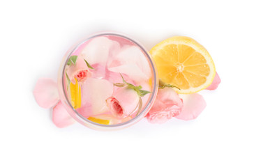 Tasty refreshing lemon drink with roses on white background, top view