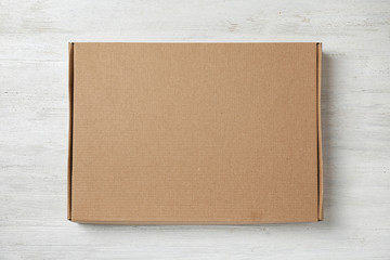 Cardboard box on white wooden background, top view