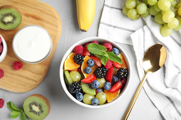 Fresh tasty fruit salad on grey table, flat lay