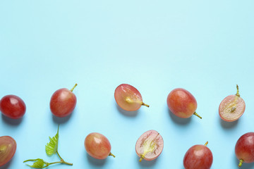 Flat lay composition with fresh ripe juicy grapes on light blue background, space for text