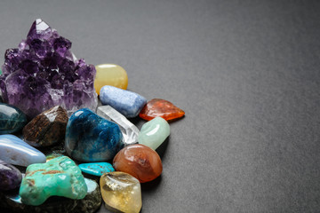 Different gemstones on dark table, space for text