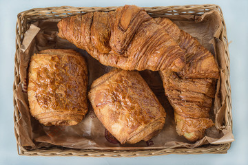 Traditional french croissants in the wicker basket close up, top view