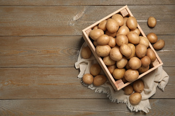 Raw fresh organic potatoes on wooden background, top view. Space for text