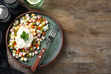 Delicious salad Olivier on wooden table, flat lay. Space for text