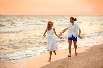 Young couple having fun on beach at sunset