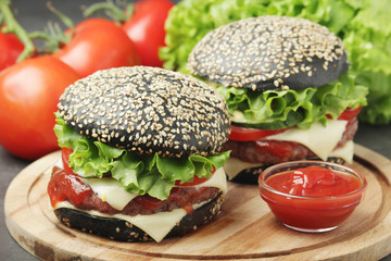 Two black burgers with vegetables and beef meat	