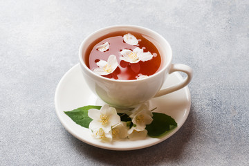 Cup of tea with Jasmine flowers on a gray table with copy space.