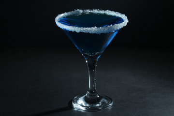 A glass with blue martini cocktail