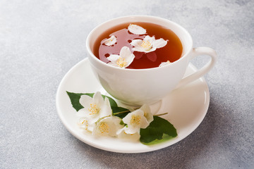 Cup of tea with Jasmine flowers on a gray table with copy space.