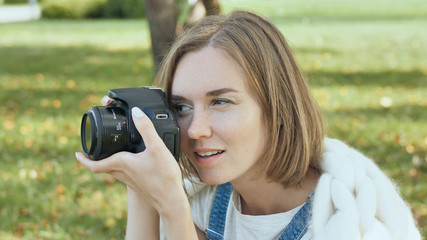The girl takes pictures of nature in the park in the summer.