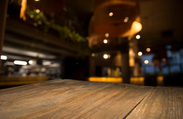 Empty wood table top on blur light gold bokeh of cafe restaurant in dark background