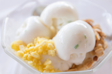 Coconut ice cream with nuts in glass bowl.