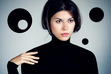 Strange fashionable portraits of a young woman in a black jumper and an unexpected hairstyle.