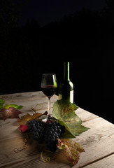 Red wine bottle and wine glass on a wooden table
