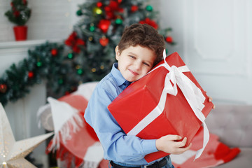 Teen boy hugs Christmas gift box.
