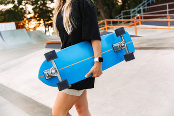 Attractive funky teenage girl carrying longboard