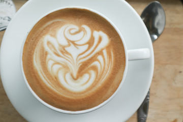 Coffee cup latte art in heart shape with a cup of dark coffee and dark chocolate on wooden table.Frothy drink for coffee break after working or weekend meeting