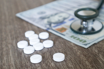 medicine pill and Medical stethoscope on 100 dollar banknote background.Healthcare insurance and medical treatment cost concept