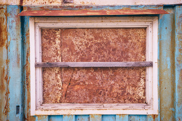 Rusty window. Boarded up window in a blue coloured house.