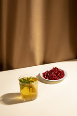Bright red pomegranate seeds with cocktail drink on white table