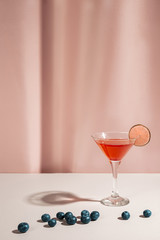 Classic margarita cocktail with lemon and riped blue berries on white table
