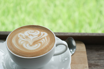 Coffee cup latte art in heart shape with a cup of dark coffee and dark chocolate on wooden table.Frothy drink for coffee break after working or weekend meeting