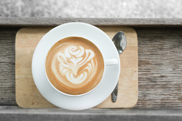 Coffee cup latte art in heart shape with a cup of dark coffee and dark chocolate on wooden table.Frothy drink for coffee break after working or weekend meeting