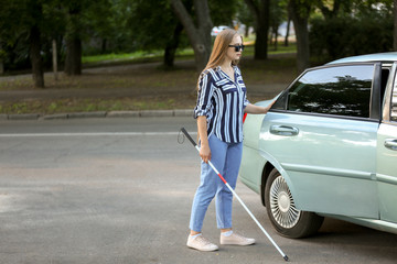 Young blind woman opening car door