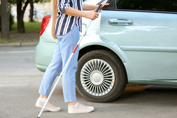 Young blind woman opening car door