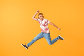 Fototapeta na wymiar Jumping young man against color background
