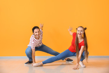 Cool young couple dancing against color wall