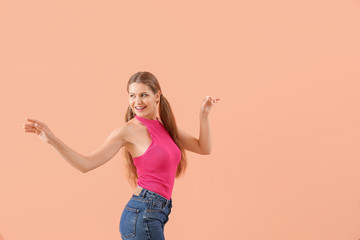 Beautiful young woman dancing against color background
