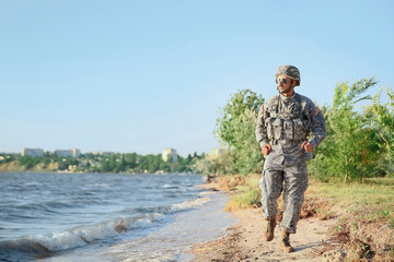 Naklejka premium Running soldier in camouflage near river