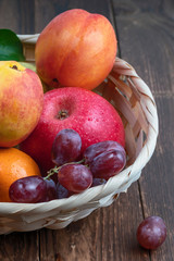 fresh fruits in a straw basket on a dark wooden background