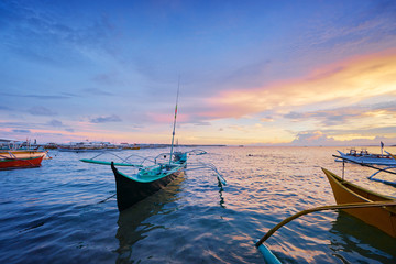 Beautiful colorful sunset on the seashore with fishing boats. Philippines, Siargao Island.