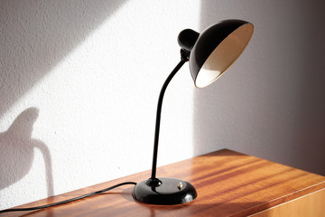 an antique black table lamp from the 20s bauhaus era standing on an old desk commode isolated on...