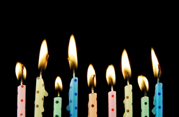 Many colorful birthday candles burning on black background